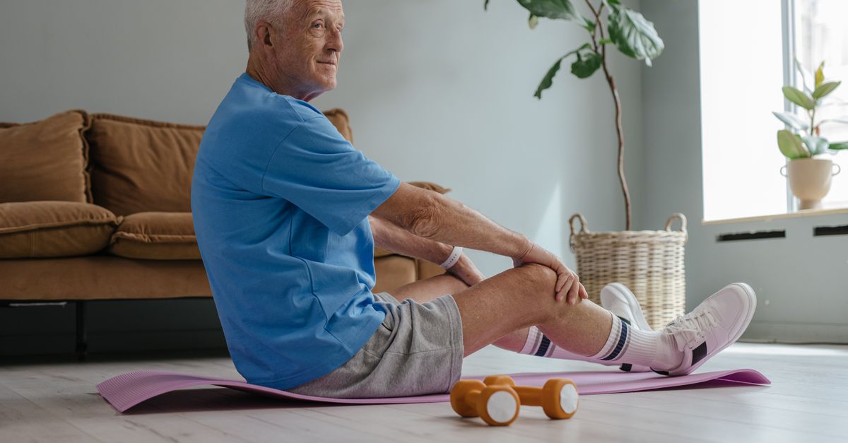 Elderly man exercising at home with yoga and weights for a healthy lifestyle.